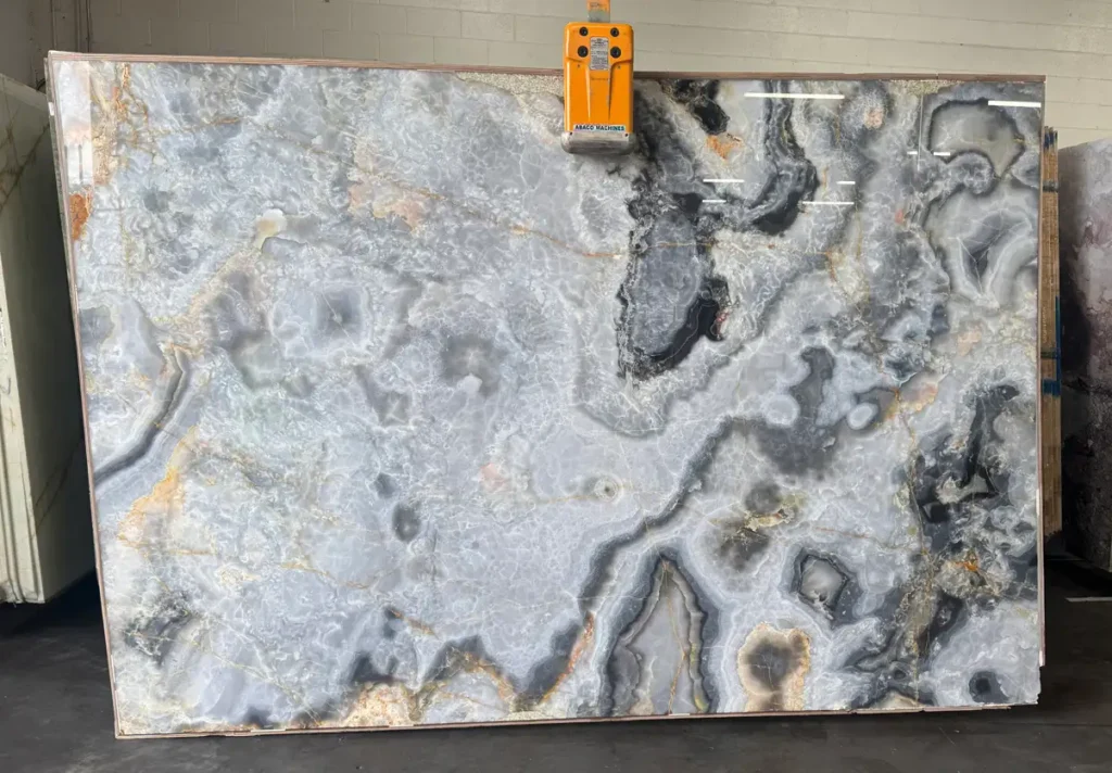 Black Onyx natural stone slab with translucent gray crystals and amber veining.