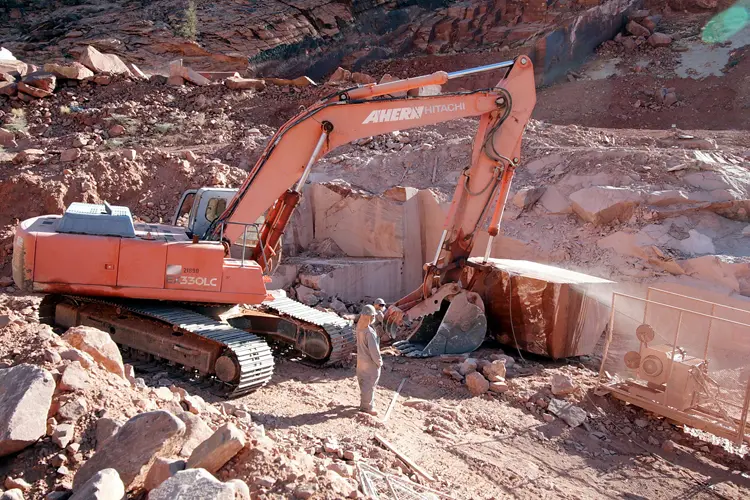 Excavator extracting a Las Vegas Rock meta quartzite block at the Nevada quarry for architectural block selection.