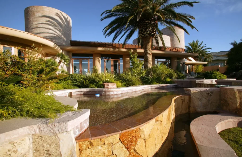 Luxury residential landscape showcasing Tupelo Honey meta quartzite used for retaining walls, water features, pool surrounds, and custom natural stone landscaping.