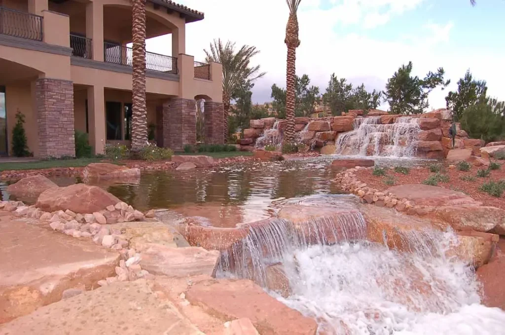 Sierra Smoke Meta Quartzite used in luxury residential landscape architecture featuring waterfalls, ponds, and natural stone hardscape.
