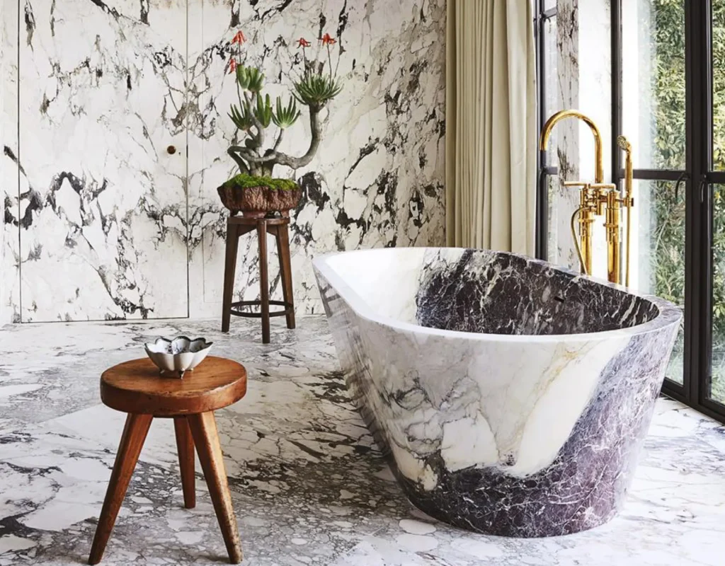 Custom carved natural stone bathtub with dramatic black, white and grey veining in a luxury residential bathroom.
