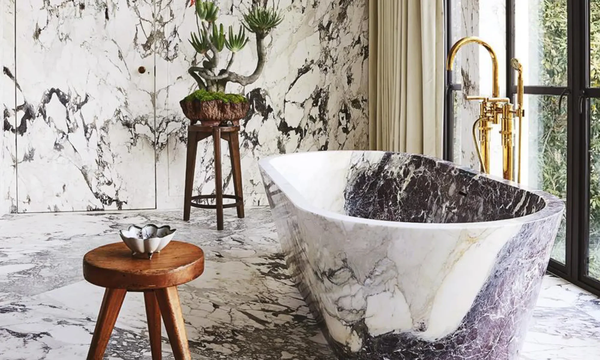 Custom carved natural stone bathtub with dramatic black, white and grey veining in a luxury residential bathroom.