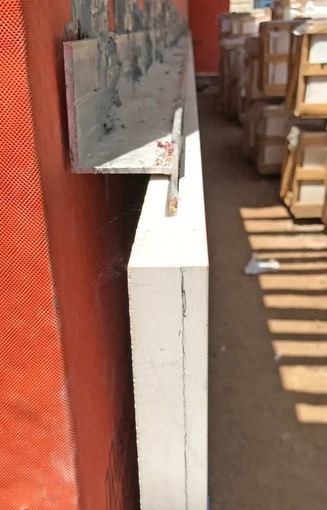 Kerf-cut natural stone cladding panel with metal anchoring rail for custom architectural stone installation
