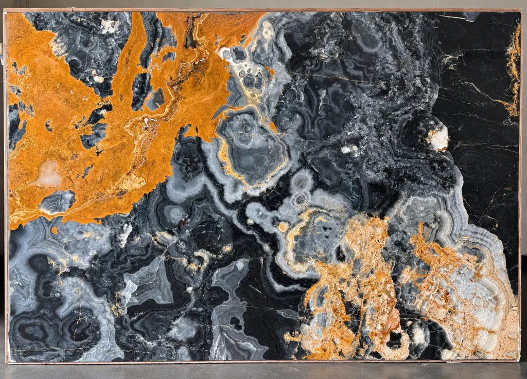 Black Onyx slab featuring dramatic charcoal-black and silver-gray crystalline formations, intricate concentric banding, and bold amber-gold mineral deposits.