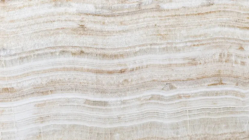Close-up of Ivory Onyx Extra showing fine horizontal layers of ivory, cream, beige, and warm taupe with gently undulating natural patterns.