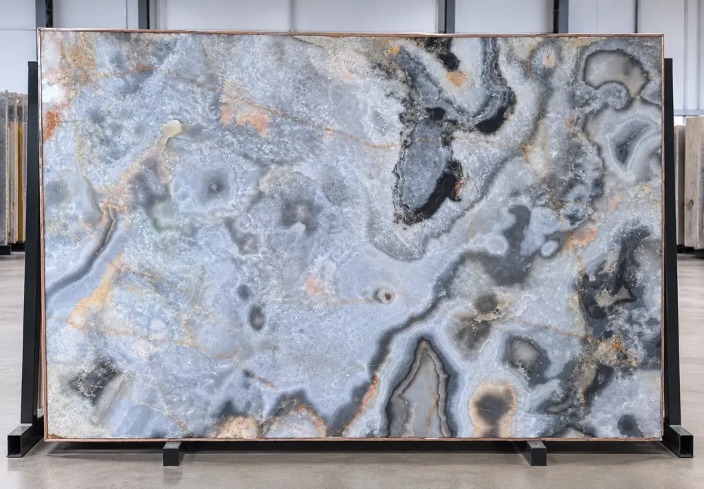 Silver Grey Onyx slab 30 displayed on an A-frame, featuring translucent silver-gray formations, charcoal-black veining, and subtle gold mineral accents.